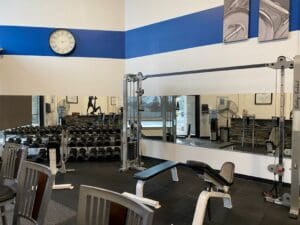 A gym with many mirrors and some chairs